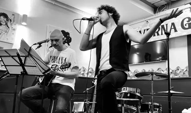 David tocando la guitarra acústica, y Marcos cantando en un concierto de Conversiones